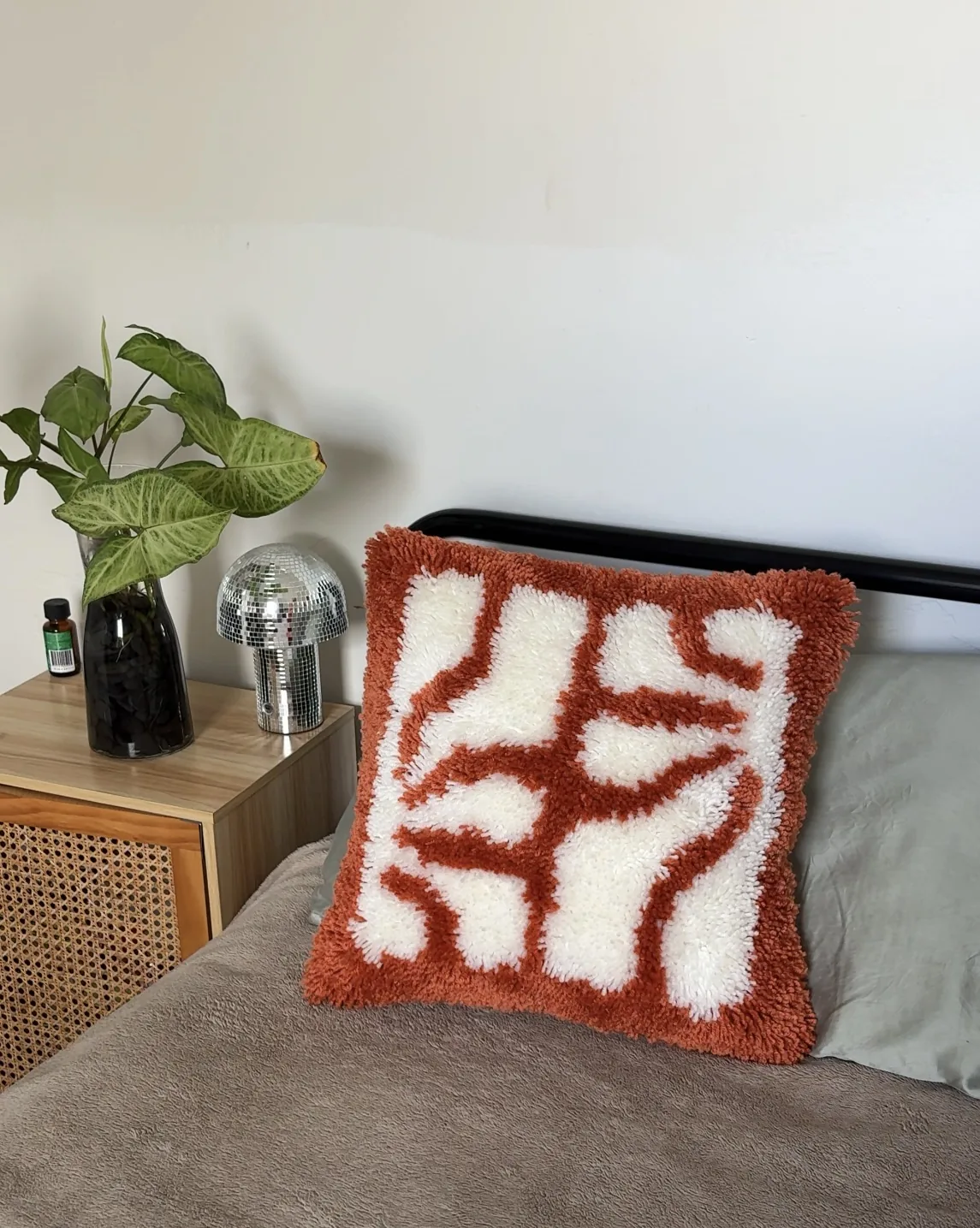 Handmade latchhook cushion with palm design styled on a bed